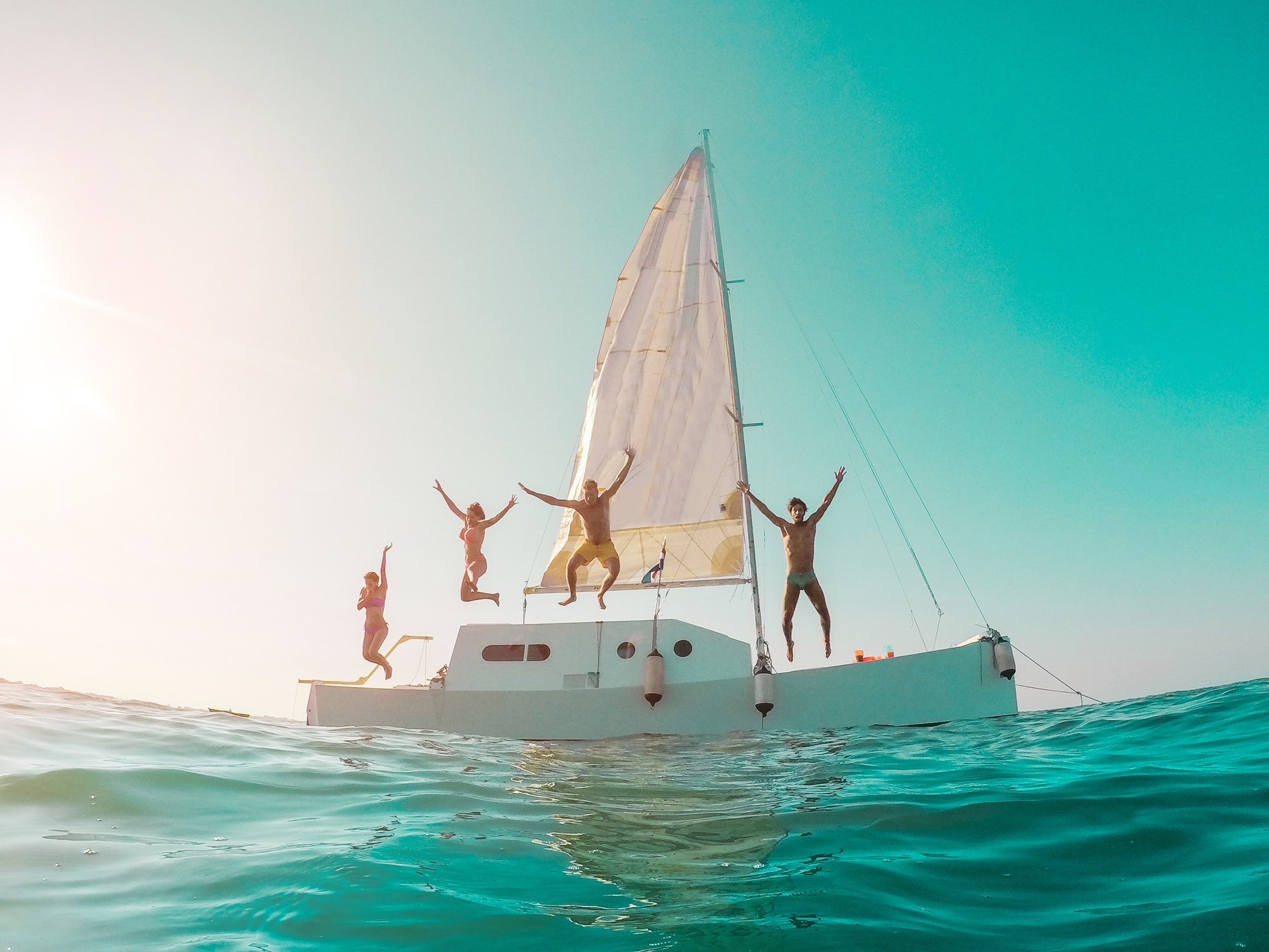 Happy crazy friends diving from sailing boat into the sea