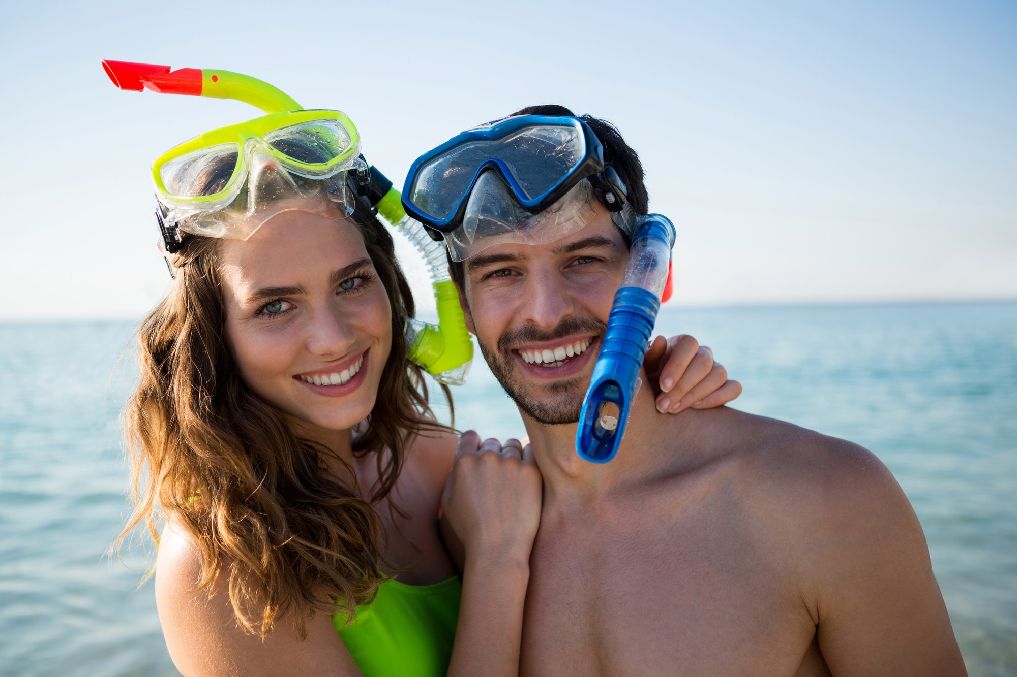 Portrait of smiling young couple wearing scuba masks at beach