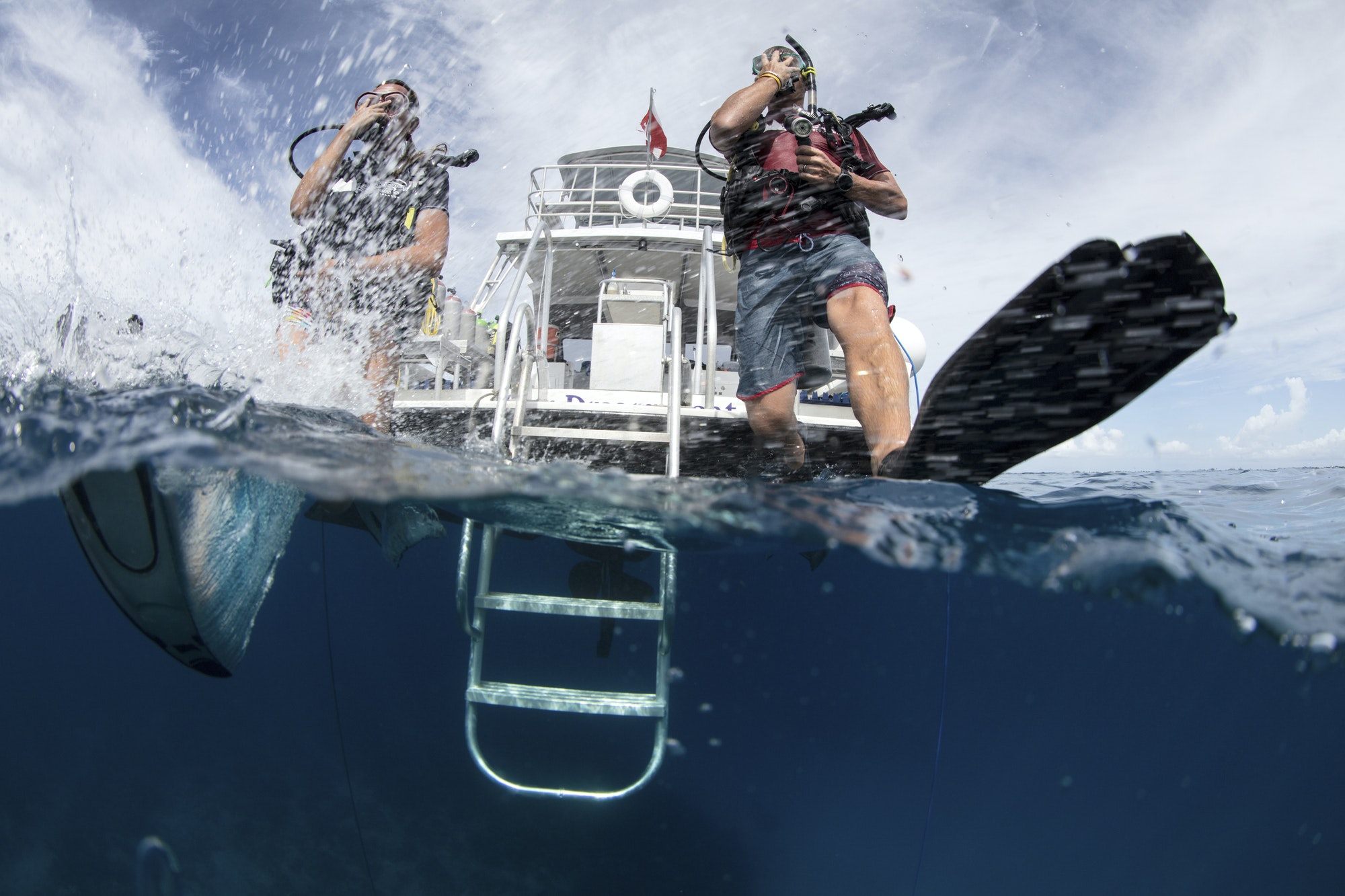 Scuba divers enter water taking a giant stride.
