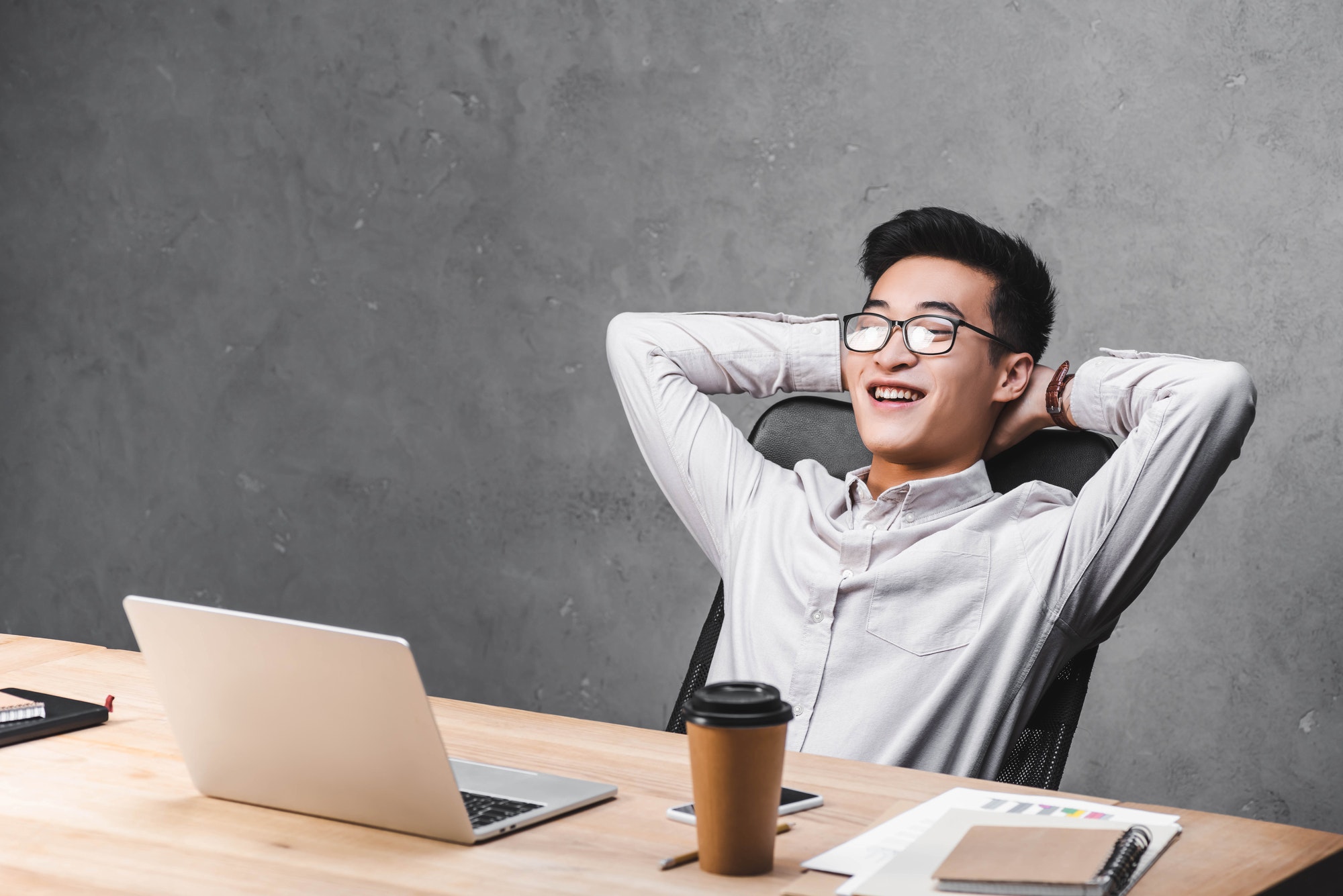 smiling asian seo manager sitting at table with crossed arms